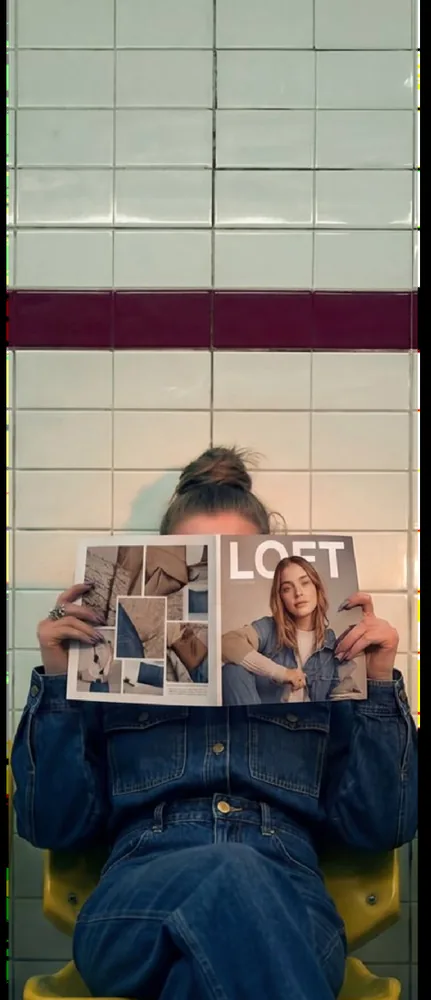 Model reading a magazine against a tiled wall. AI campaign image